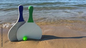 Beach tennis paddle rackets and green balls on sandy beach with waves breaking on shore Stock Video