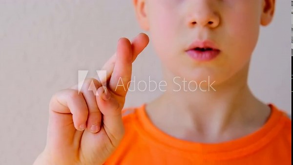 Close-up of child's crossed fingers for luck, 9-year-old boy making motivational gesture symbolizing hope, support, optimism concept emotional development, encouraging gestures, childhood optimism