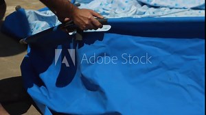 Close-up of a man's hands assembling the base of a frame pool. Installing a blue pool in the backyard for the summer season