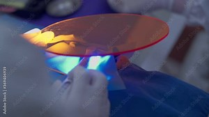 Dentistry concept, a hygiene disinfection operation working procedure, dentist's hand holding an UV protection seal, using ultraviolet light for teeth fillings procedure, whitening tooth