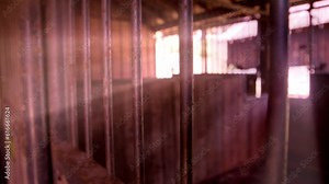 Light rays pouring in over the bars of an empty jail cell.