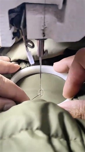 stitching dark green fabric using a sewing needle for professional handmade embroidery production