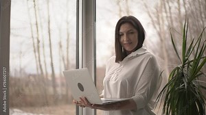 woman and laptop. woman at the window. laptop. slow motion video. High-quality shooting in 4K