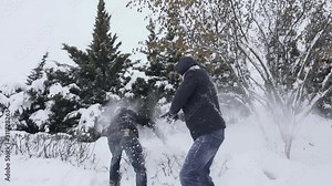 Guys throw snow at each other in winter snowfall in daytime in slow motion. Men messing and fooling around. Fun and carefree time. Immunity and health.