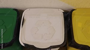 Waste bins, recycling and separate waste, waste separation. Color-coded recycling bins for glass, paper, and plastic with recycling symbols on lids.