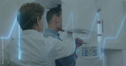 Medical tech positioning patient under rotating Xray arm ensuring head alignment as ECG pulsing