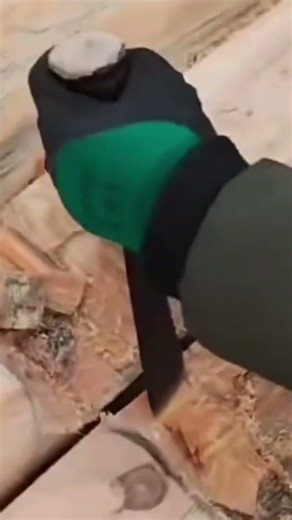 A large piece of wood being scraped by a man using a special tool.