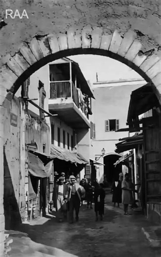 📸✨ Plongée dans le passé de Rabat ! Sous cette magnifique arche, on découvre la rue du Mellah à Rabat, un quartier historique où vivait autrefois la communauté juive. 🕍 Les ruelles étroites, les façades blanchies et les petites échoppes racontent la vie quotidienne d’une époque révolue. On imagine les artisans, les marchands, les enfants courant entre les étals... 🧵🪔👣 Cette photo exceptionnelle date probablement des années 1920-1930, durant le protectorat français au Maroc 🇲🇦🇫🇷. Un témo