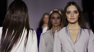 Fashion design female clothes woman on podium slow motion spotlights scene. Defile beautiful girl in colorful dress on catwalk model show close up evening vogue 4K.