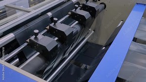 Close up view: automatic plastic bag making machine - production of black trash bags at packaging exhibition, factory. Representation of manufacturing, recycling, industry and technology equipment