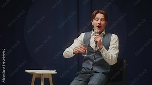 StandUp cafe, comedy concert. Man telling jokes on stage. Male comedian speaks with audience using microphone, humorous monologue. Mentor coach training. Public speaking masterclass.