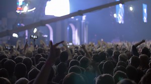 Concert audience with hands up and bright stage lights