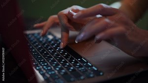 This image captures a closeup view of hands actively typing on a laptop keyboard in a softly lit environment