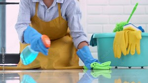 4k video of Housekeeper maid wearing rubber gloves with cloth cleaning or applying floor care and cleaners at home, housework and housekeeping concept.