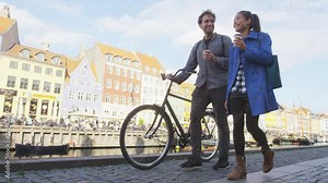 Copenhagen people. Couple walking in Nyhavn, old port. Famous tourist attraction destination in Denmark Young multiracial happy couple with bicycle bike and coffee. RED EPIC.