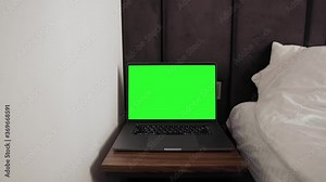 Close up shot of modern chroma key green screen MacBook Pro 16 inch laptop computer set up for work on desk at night - remote work, technology concept, video template. Hotel room environment