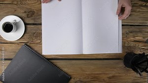 Woman turning pages of blank magazine on table, top view Stock Video