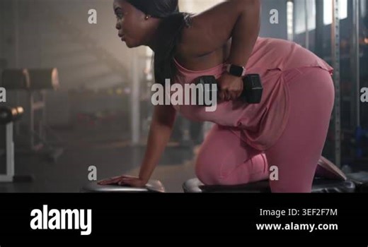 Female partners performing one-arm dumbbell rows on bench at gym, partner approaching guiding form. Fitness, training, weights, workout, spotter, coaching, athletic Stock Video Footage - Alamy