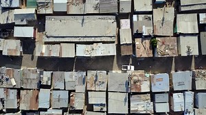 Aerial top-down view of slum a heavily populated urban informal settlement characterized by substandard housing and squalor showing people walking through streets and rusty metal home roof tops 4k Stock Video