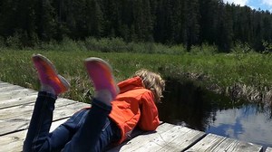 Girl Leaning Over a Wooden Pier at a Cottage