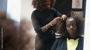 Hairdresser making crochet braids using a latch hook needle to a customer in an afro hair salon