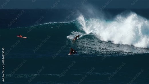 Big wave surfing in Hawaii on Waimea Bay. Person surfs the huge ocean wave breaking on the Hawaiian shore in Waimea Bay. Surfer rides the big wave in Hawaii. Oahu island