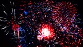 Fireworks Exploding in the night sky in red, blue and white colours.