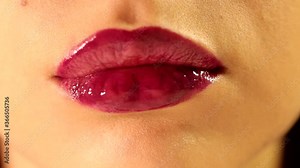 Close up shot of beautiful woman tongue licking her lips with bright deep red plum berry glossy lipstick tint lipgloss