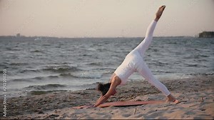 young woman doing yoga on the beach on the background of water and sunset. kundalini yoga