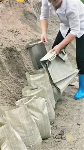 Filling multiple sandbags with sand using metal shovels and securing them for flood wall protection