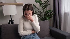 Unhappy pregnant young woman suffering from nausea, having vomit feeling sick covering mouth sitting on sofa, touching belly having problem throwing up from food poisoning, girl with morning sickness