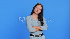 Funny comical playful young woman making silly facial expressions and grimacing, fooling around, showing tongue, idiotic expression. Girl isolated alone on blue studio background. People lifestyles