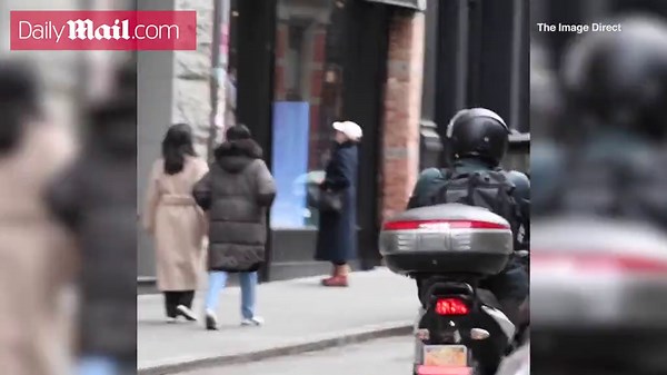 Meryl Streep keeps her head low under a ball cap bundled up in a cloak-like coat