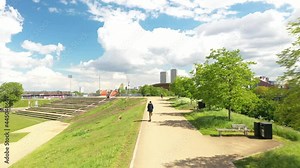 Tracking person riding electric scooter. Back view of man riding on path in town park. Reducing carbon footprint