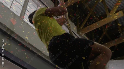 Climber grabbing rope, climbing in fitness gym to ceiling via leg clamp, particles showing watch