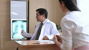 The Asian smart doctor was talking to his Asian woman patient about her lung X-ray.
