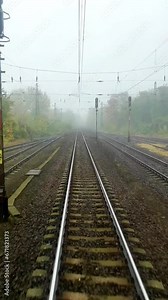 Front view or driver cabin view of a train travelling on tracks in the city with autumn trees during fall
