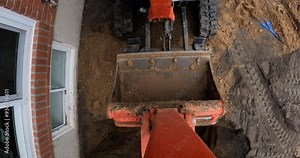 Mini excavator preparing to dig up house foundation for repairs - fpv view from bucket
