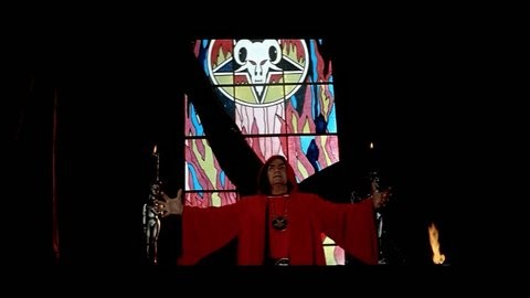 US - 1975 - in this horror film, a man prays to God while a satanic preacher tries to get him to join his cult. The man resists but turns around in astonishment when the leader points out his mother.