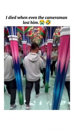 @Trend_io on Instagram: "This video features a young man navigating a vibrant, kaleidoscopic mirror maze. The environment is filled with colorful, pattern-covered pillars and floor-to-ceiling mirrors that create a disorienting infinity effect. As he moves through the passage, he repeatedly walks into glass panels he mistakes for open paths, resulting in several comical "thuds" and fits of laughter from both him and the person filming. The maze's design uses bright pink, blue, and green geometric