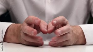 hands of a businessman in a white shirt lie on the table and tap his fingers on his fingers. closeup. obsessive hand gestures while waiting or thinking.