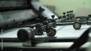 Technology of fully automated press machine in typography. Industrial equipment of printing industry operating during daily newspaper production. Putting sheets to conveyor for print. Printing house.