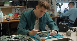 young concentrated technician or Engineer installing CPU microprocessor to motherboard socket on workplace in the office. Concept of repairing, upgrade, service, electronics and technology of computer