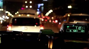 The digital taxi meter on the dashboard of cab shows kilometer and cost. Night taxi ride in traffic jam.