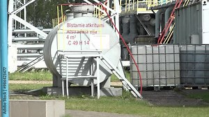Sigulda, Latvia - August 10, 2024 - Industrial hazardous waste storage tank labeled with safety information, pipes, and containers, located outdoors in an industrial area.