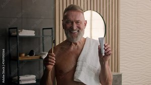 Close up Caucasian smiling carefree old man healthy toothy smile enjoy tooth treatment oral hygiene happy male retired pensioner in bathroom holding showing teeth brush and toothpaste dental procedure