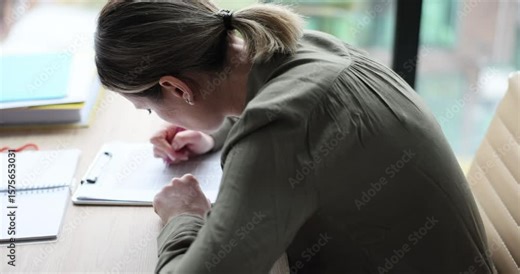 Focused businesswoman writes notes bending over desk in office. Blonde female manager fills form on clipboard working in corporate environment