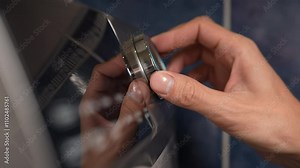 Optimizing washing machine settings for laundry in snug utility room. Closeup of male hand press switch and select mode of washing machine. Concept of modern technology in household chores.