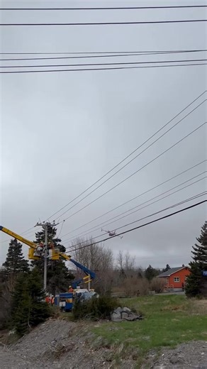 Newfoundland Power crews work at the edge of the evacuation zone of the fire in the Adam’s Cove area to help ensure safety for first responders and smooth restoration of power, once possible. A water bomber flies overhead at a safe distance from power lines (the video angle makes it look closer). Our thoughts continue to be with those impacted. Newfoundland Power will continue to work closely with our safety partners and extends our gratitude to those fighting the fires in the province. | Newfou