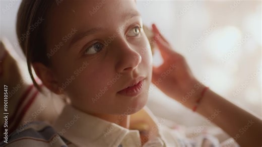 Side view close up shot of curious gen Alpha Caucasian girl listening to seashell holding it up to her ears, imagining sound of ocean